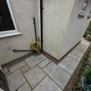 New sandstone paving laid neatly around the side of a house